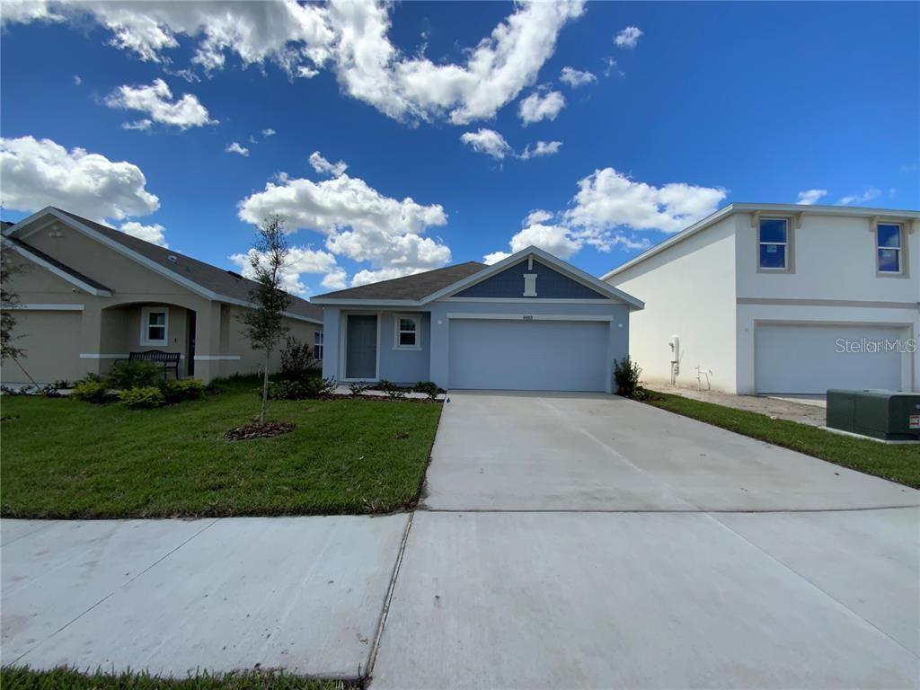 A light blue single-story house with a two-car garage sits between two neighboring homes — 4603 SAND DOLLAR WAY, ZEPHYRHILLS, FL