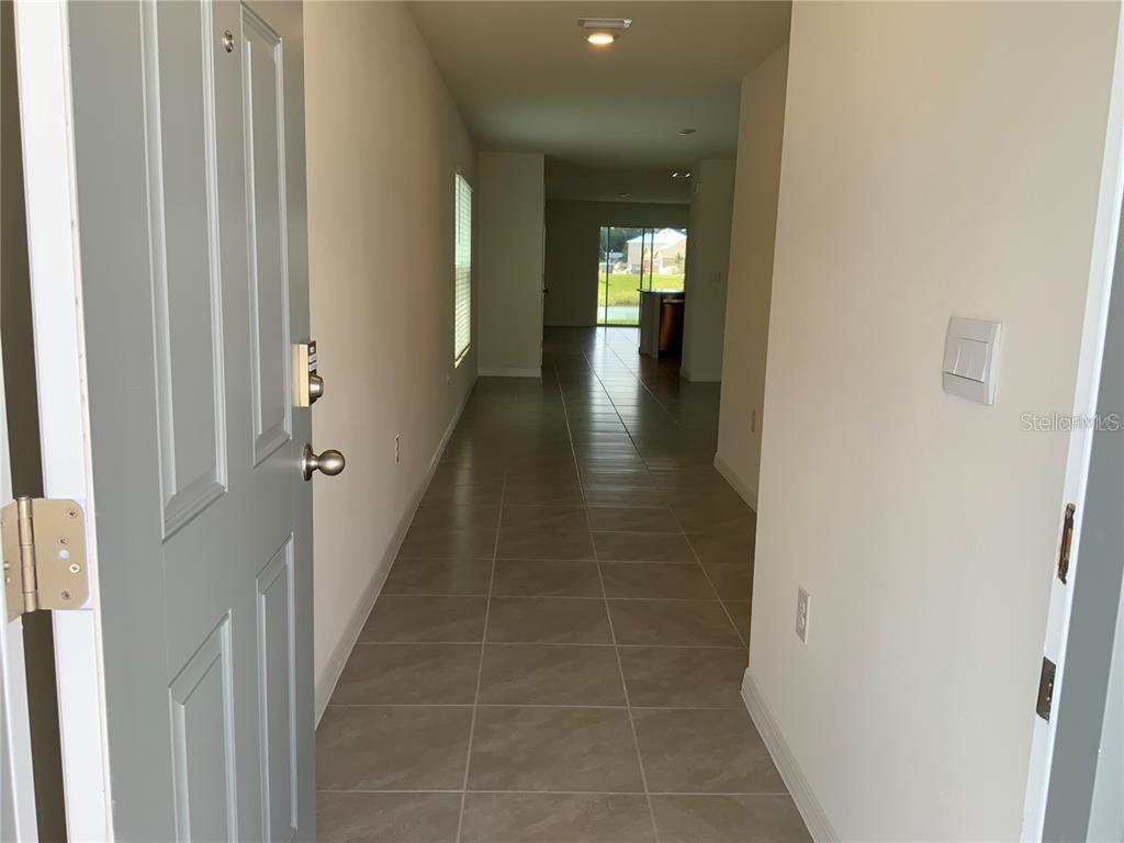 An entryway leads into a tiled hallway with a view of the backyard — 4603 SAND DOLLAR WAY, ZEPHYRHILLS, FL