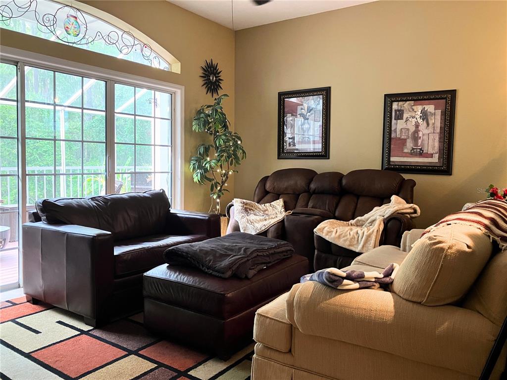 A living room features three sofas, a large ottoman, and a window with stained glass — 2015 VISTA DEL SOL CIRCLE UNIT 108, LUTZ, FL
