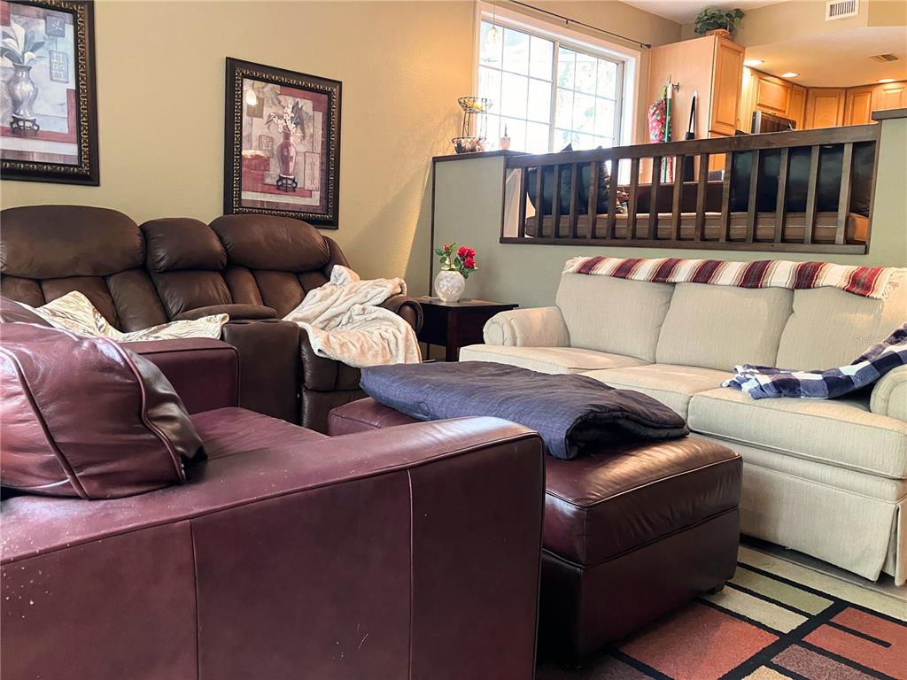 A living room features a brown leather sofa, a beige sofa, and a dark ottoman — 2015 VISTA DEL SOL CIRCLE UNIT 108, LUTZ, FL