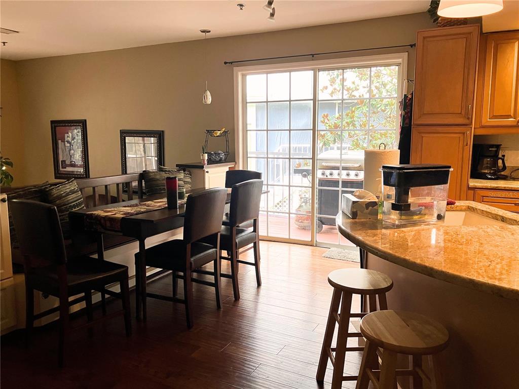A dining area with a wooden table and chairs sits next to a kitchen island — 2015 VISTA DEL SOL CIRCLE UNIT 108, LUTZ, FL