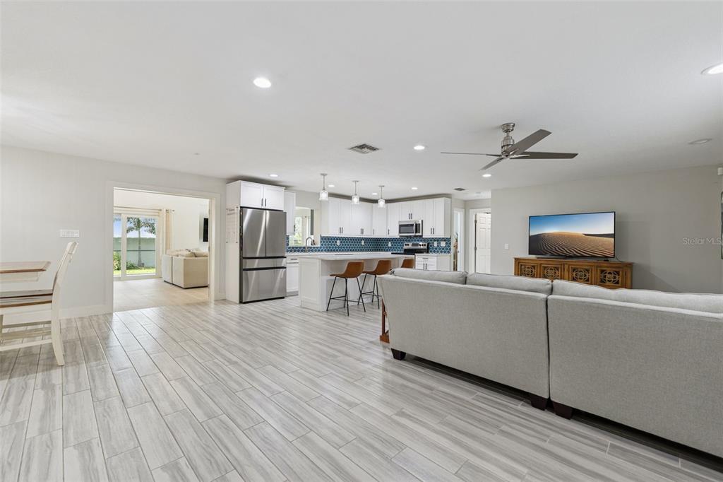 An open-concept living room and kitchen feature light wood-look tile floors and white cabinetry — 302 W COMANCHE AVENUE, TAMPA, FL