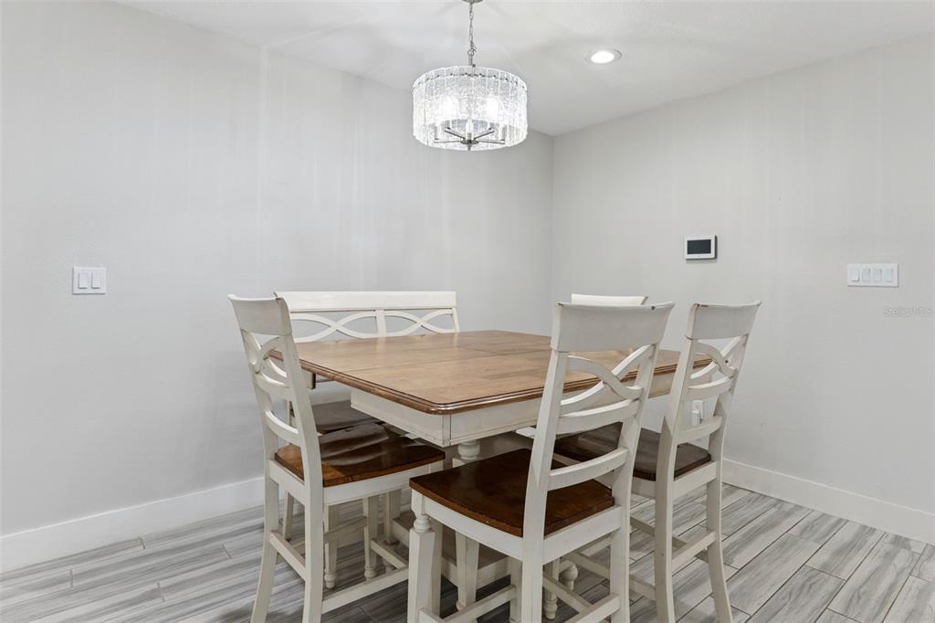 A dining area features a wooden table with white chairs and a crystal chandelier — 302 W COMANCHE AVENUE, TAMPA, FL