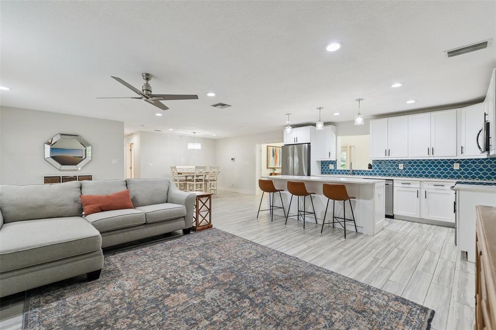 An open-concept living room and kitchen featuring white cabinetry, a kitchen island, and tile flooring — 302 W COMANCHE AVENUE, TAMPA, FL
