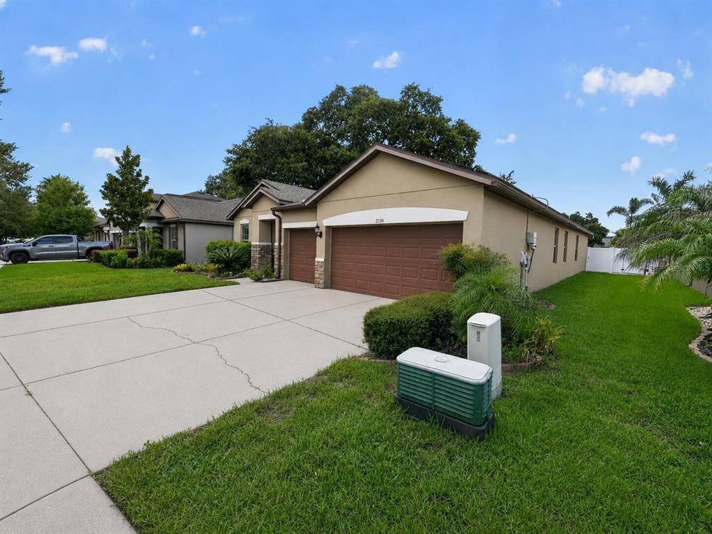 A tan single-story house with a two-car garage and a concrete driveway under a blue sky — 2130 LANDSIDE DRIVE, VALRICO, FL