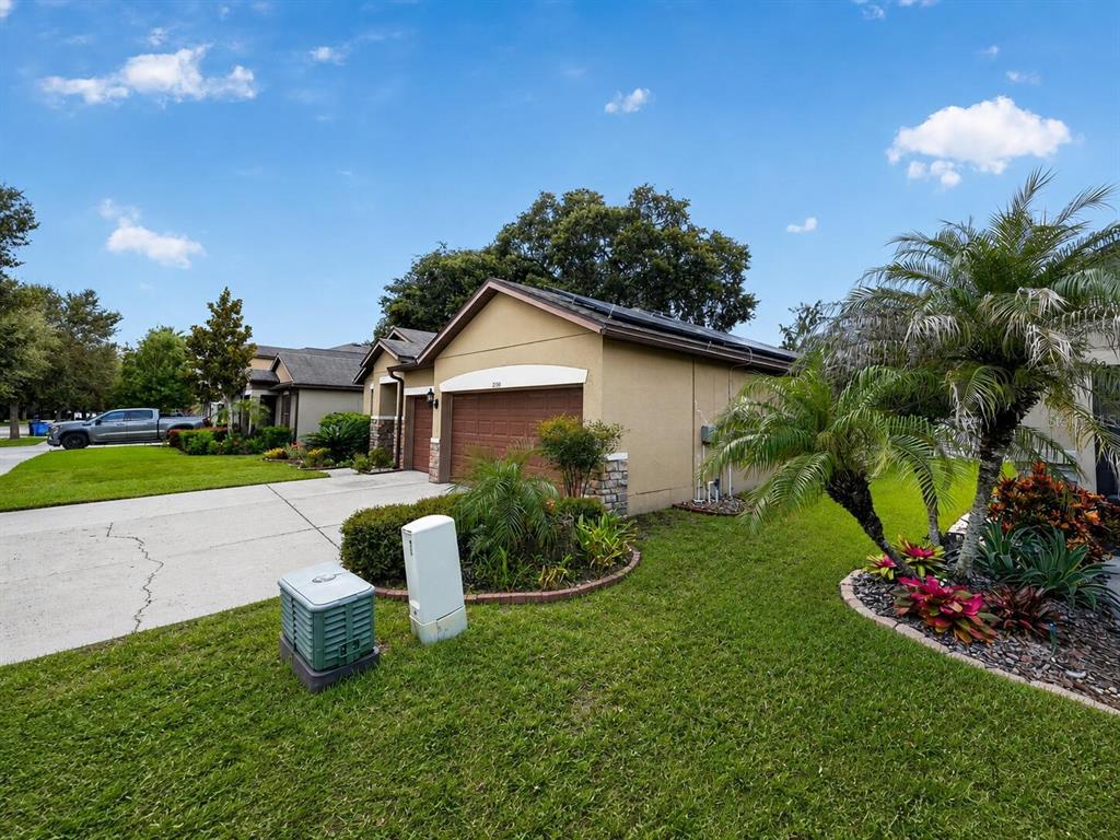 A tan single-story house with a two-car garage, a concrete driveway, and landscaped front yard — 2130 LANDSIDE DRIVE, VALRICO, FL