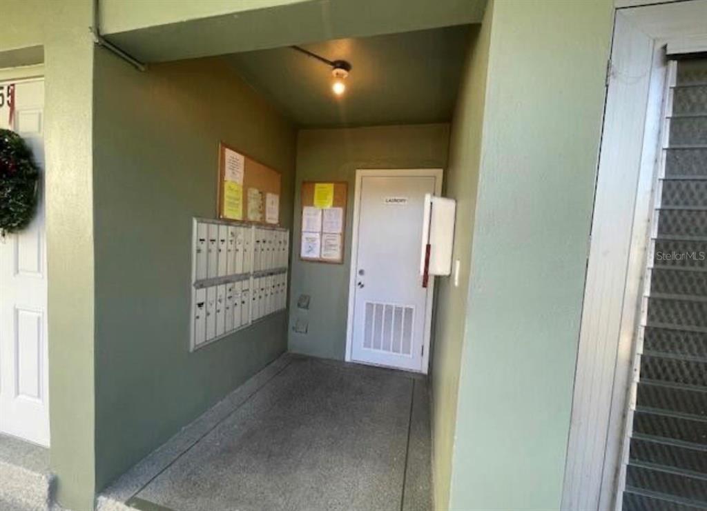 A covered outdoor entryway features a bank of mailboxes, a laundry room door, and notices — 66 EASTHAMPTON UNIT C, WEST PALM BEACH, FL