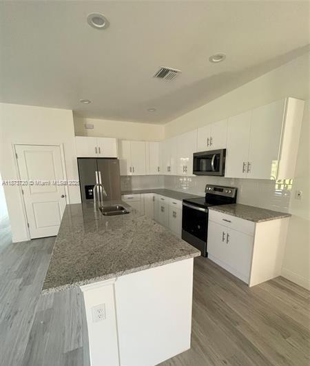 A modern kitchen features white cabinetry, granite countertops, a center island, and stainless steel appliances — 3034 E Briarwood Cir, La Belle FL 33935, LA BELLE, FL