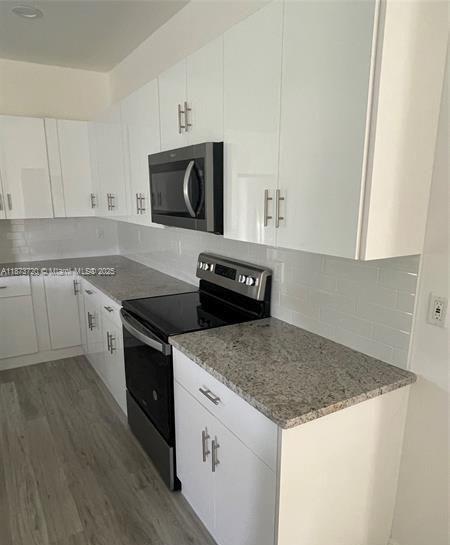 A kitchen features white cabinets, granite countertops, stainless steel appliances, and light wood-look flooring — 3034 E Briarwood Cir, La Belle FL 33935, LA BELLE, FL