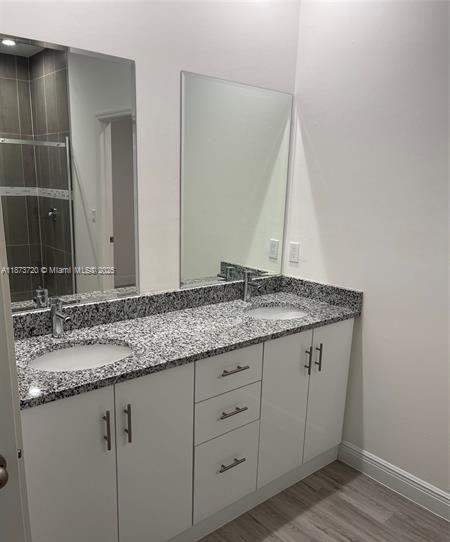 A bathroom vanity with a granite countertop, dual sinks, white cabinets, and two wall mirrors — 3034 E Briarwood Cir, La Belle FL 33935, LA BELLE, FL