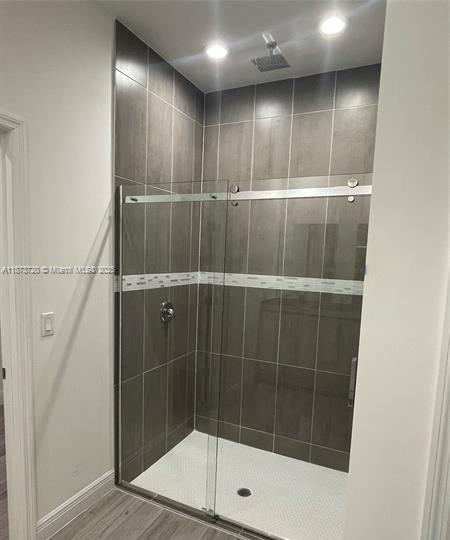A walk-in shower with gray tiled walls, a glass sliding door, and a white base — 3034 E Briarwood Cir, La Belle FL 33935, LA BELLE, FL