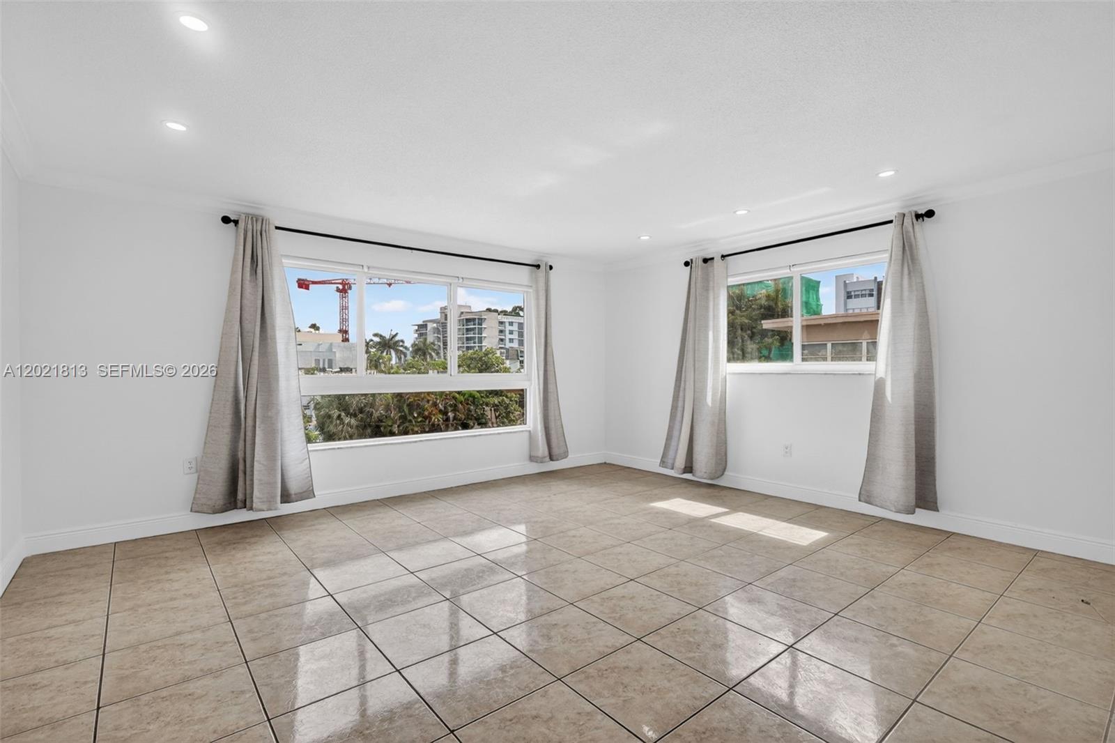 An empty room with white walls, tile flooring, and two windows with curtains — 1020 94th St # 301, Bay Harbor Islands FL 33154, BAY HARBOR ISLANDS, FL