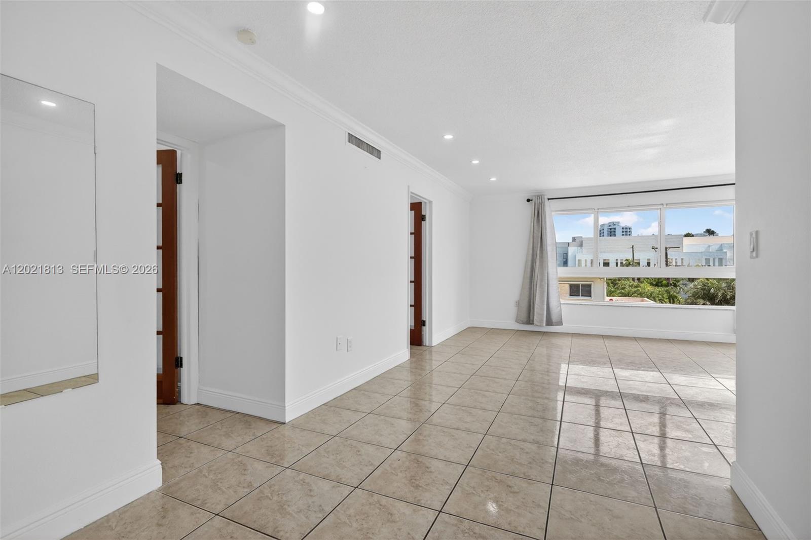 An empty room with tiled floors, white walls, recessed lighting, and a large window — 1020 94th St # 301, Bay Harbor Islands FL 33154, BAY HARBOR ISLANDS, FL