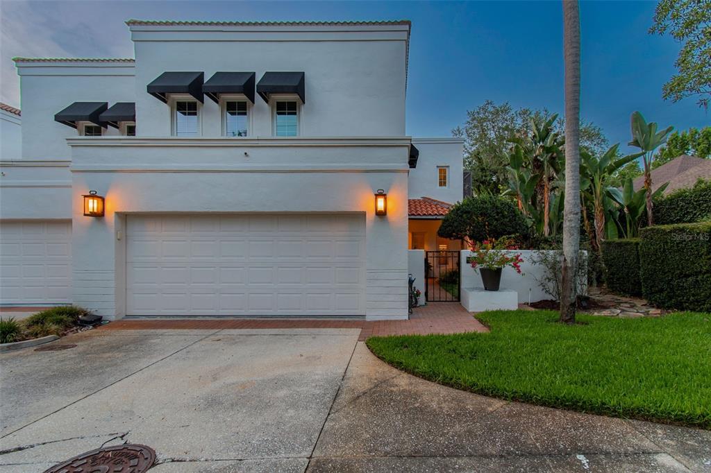 A white two-story house features a double garage, black awnings, and a gated courtyard entrance — 3133 LAKE ELLEN DRIVE, TAMPA, FL