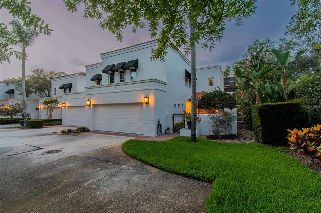 A white two-story house with a two-car garage and black window awnings at dusk — 3133 LAKE ELLEN DRIVE, TAMPA, FL