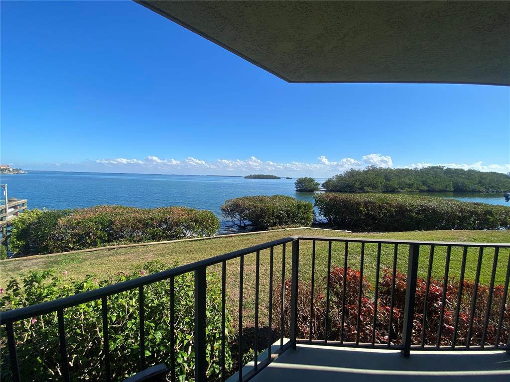 A balcony with a black metal railing overlooks a grassy lawn and the ocean — 1515 PINELLAS BAYWAY S UNIT 1, ST PETERSBURG, FL