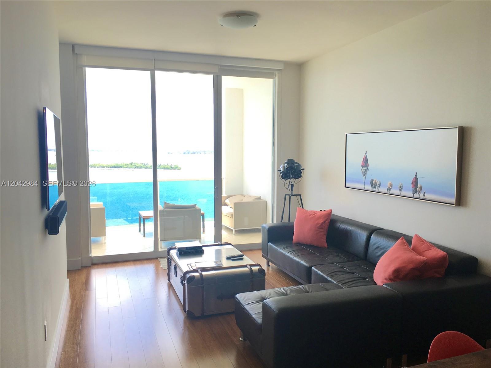 A living room features a black leather sofa, a trunk coffee table, and balcony views — 725 NE 22nd St # 14E, Miami FL 33137, MIAMI, FL