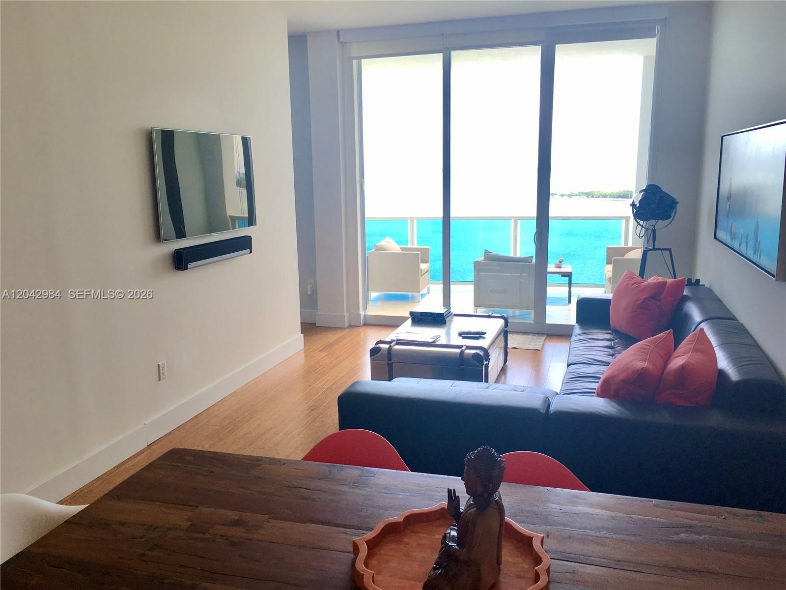 A living room features a dark leather sofa, a trunk coffee table, and ocean views — 725 NE 22nd St # 14E, Miami FL 33137, MIAMI, FL