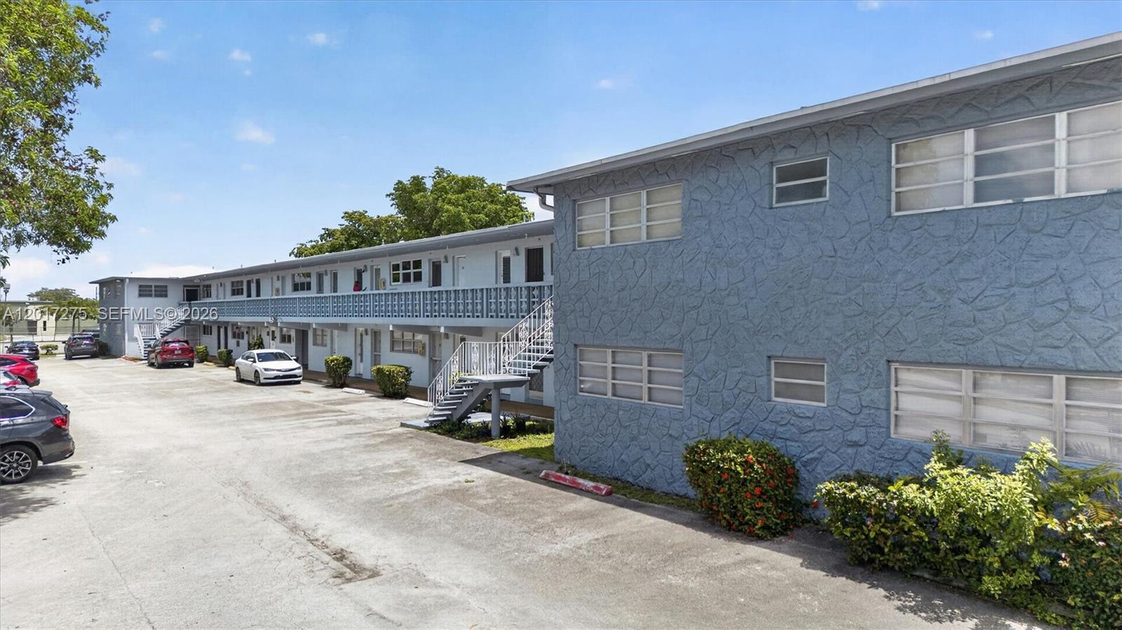 A two-story blue apartment building with an exterior walkway and a parking lot — 300 NE 191st St # 219, Miami FL 33179, MIAMI, FL