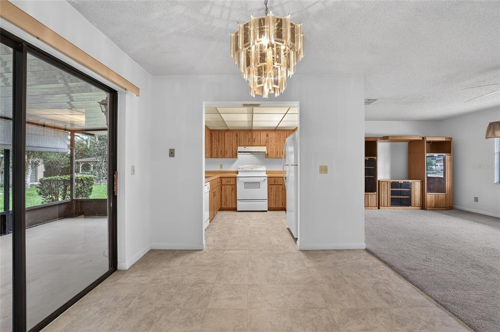 A dining area with a chandelier leads to a kitchen with wood cabinets and appliances — 610 FOURTH AVENUE, LADY LAKE, FL
