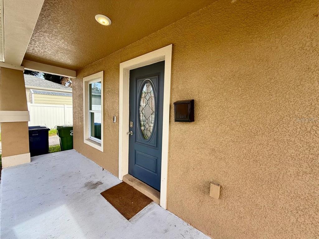 A covered porch features a blue front door with a decorative oval glass window — 2904 E COLUMBUS DRIVE, TAMPA, FL