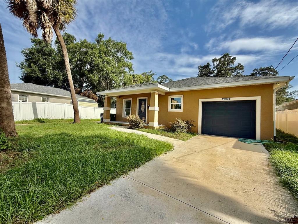 A single-story house with a tan exterior, a dark garage door, and a front lawn — 2904 E COLUMBUS DRIVE, TAMPA, FL
