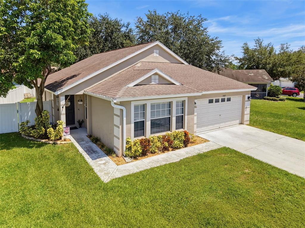 An elevated exterior view of a single-story beige house with a white garage and lawn — 11627 LEDA LANE, NEW PORT RICHEY, FL