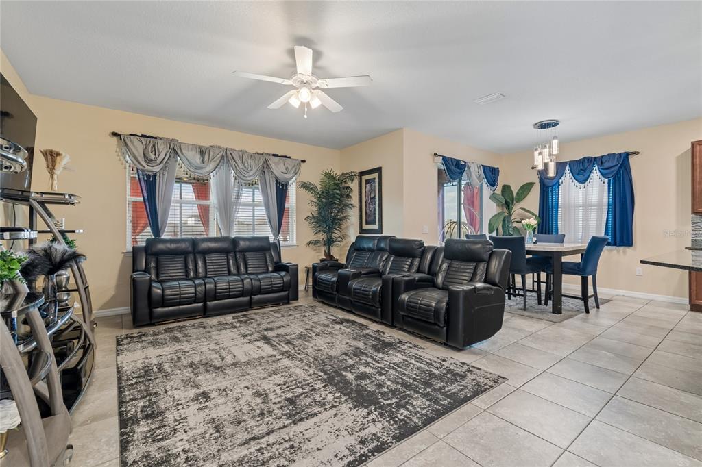 A living room and dining area with tile floors, black leather sofas, and blue curtains — 11804 BLUEGRASS FIELD COURT, RIVERVIEW, FL