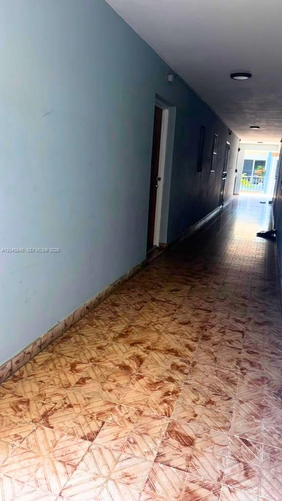 A long, narrow outdoor hallway features light blue walls and patterned tile flooring — 145 SW 30th Ct # 209B, Miami FL 33135, MIAMI, FL