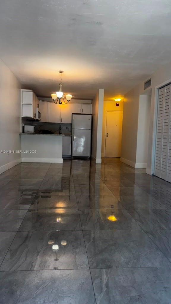 A kitchen with white cabinets and a refrigerator opens into a room with tiled floors — 145 SW 30th Ct # 209B, Miami FL 33135, MIAMI, FL