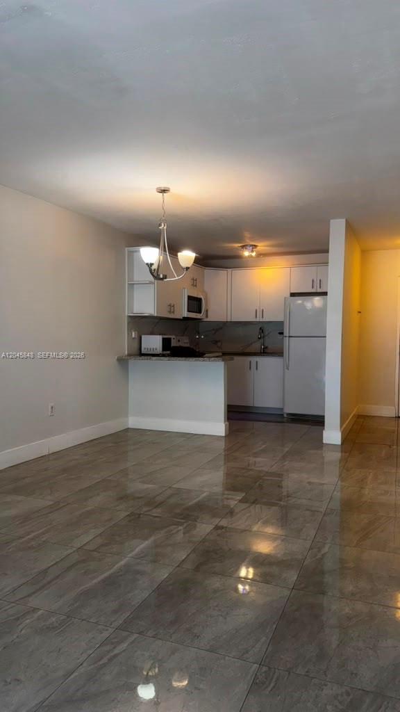 A kitchen with white cabinets and a breakfast bar opens into a tiled living area — 145 SW 30th Ct # 209B, Miami FL 33135, MIAMI, FL