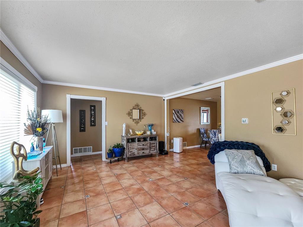 A living room with tan walls, tile flooring, and a white chaise lounge — 270 BELAIRE COURT, PUNTA GORDA, FL
