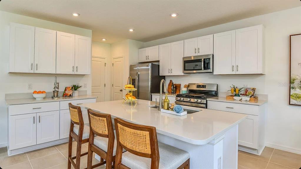 A modern kitchen features white cabinetry, stainless steel appliances, and a large central island — 13840 SHELLMORE AVENUE, PALMETTO, FL