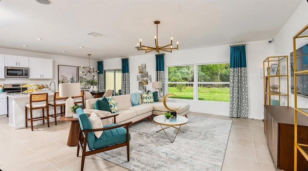 An open-concept living room and kitchen with white cabinetry, a sectional sofa, and teal accents — 13840 SHELLMORE AVENUE, PALMETTO, FL