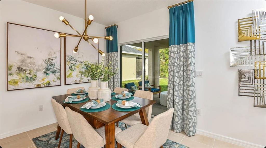 A dining room features a wooden table, modern chandelier, abstract wall art, and sliding glass doors — 13840 SHELLMORE AVENUE, PALMETTO, FL