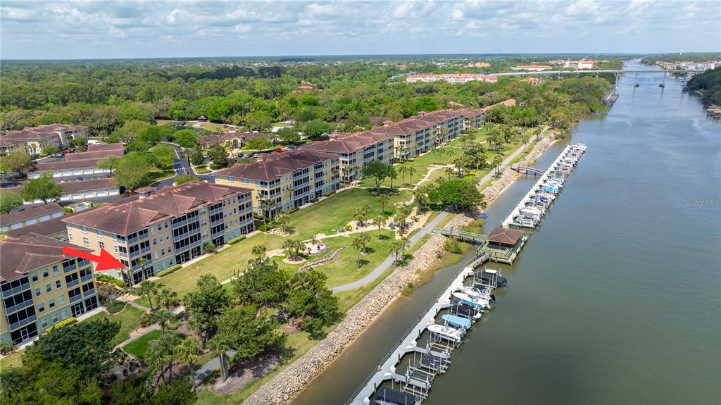 An aerial view shows a multi-story apartment building next to a river with a boat dock — 400 CANOPY WALK LN UNIT 425, PALM COAST, FL