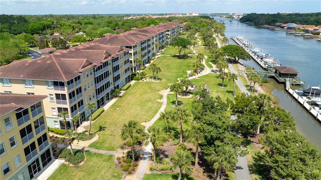 An aerial view shows a multi-story apartment complex adjacent to a grassy park and boat docks — 400 CANOPY WALK LN UNIT 425, PALM COAST, FL