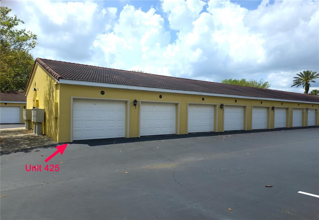 A row of yellow garage units with white doors under a dark tiled roof — 400 CANOPY WALK LN UNIT 425, PALM COAST, FL