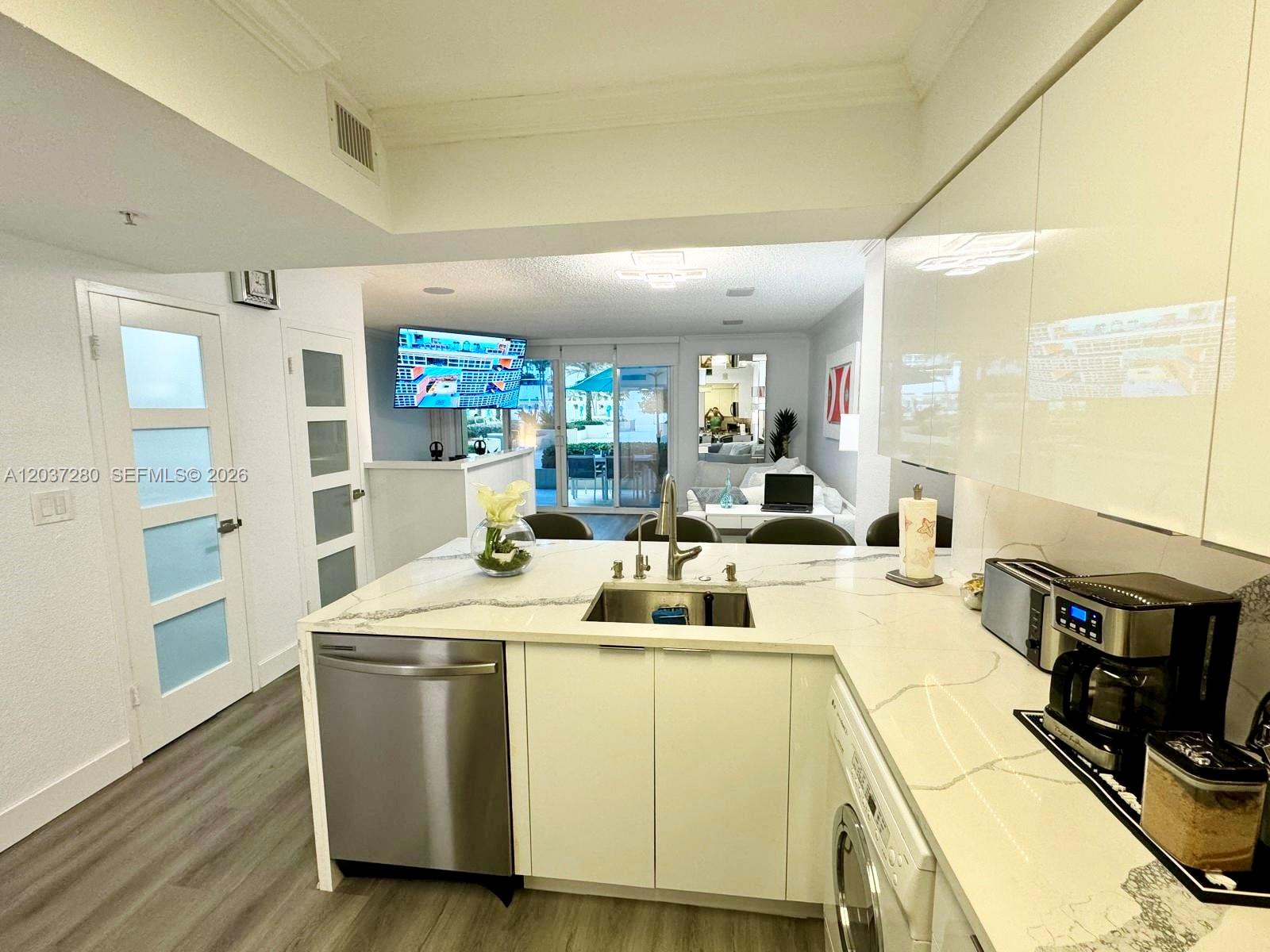 A modern kitchen features white cabinetry, a marble-patterned countertop, and stainless steel appliances — 2501 S Ocean Dr # L14, Hollywood FL 33019, HOLLYWOOD, FL