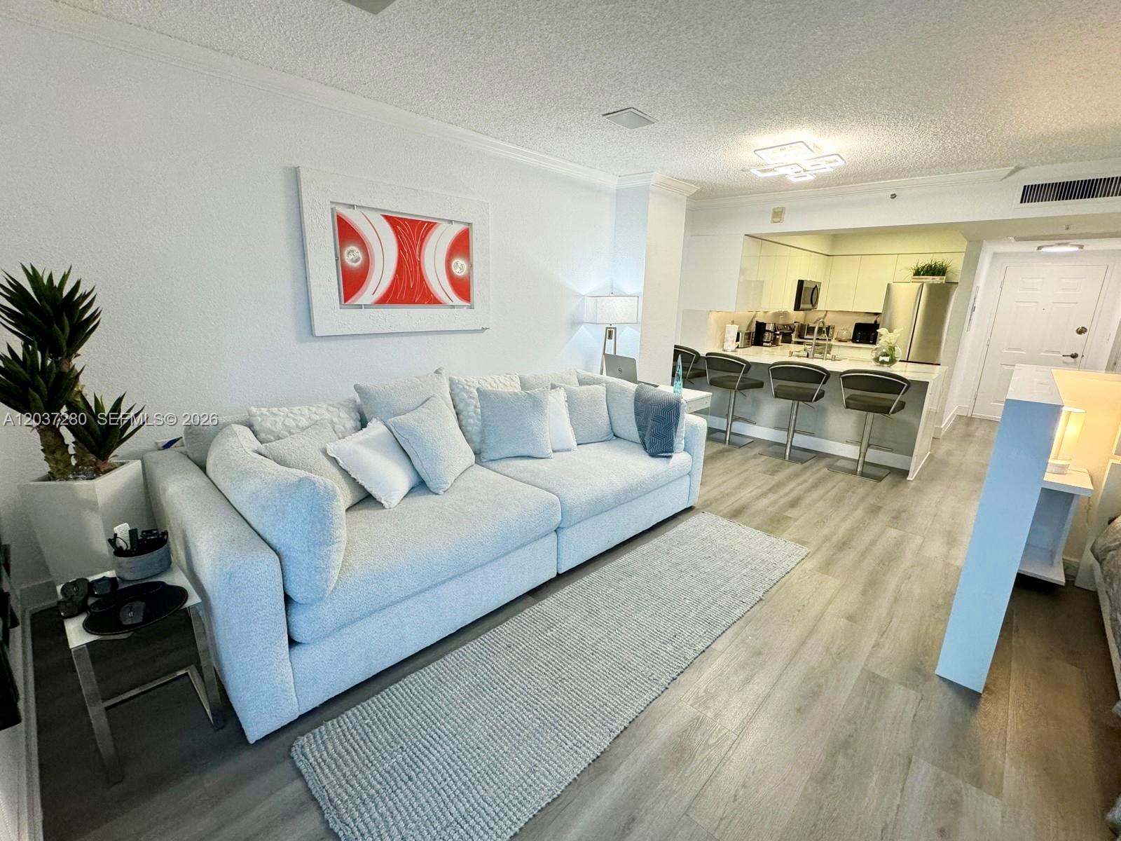 A living room with a gray sofa, area rug, and an open kitchen with bar seating — 2501 S Ocean Dr # L14, Hollywood FL 33019, HOLLYWOOD, FL