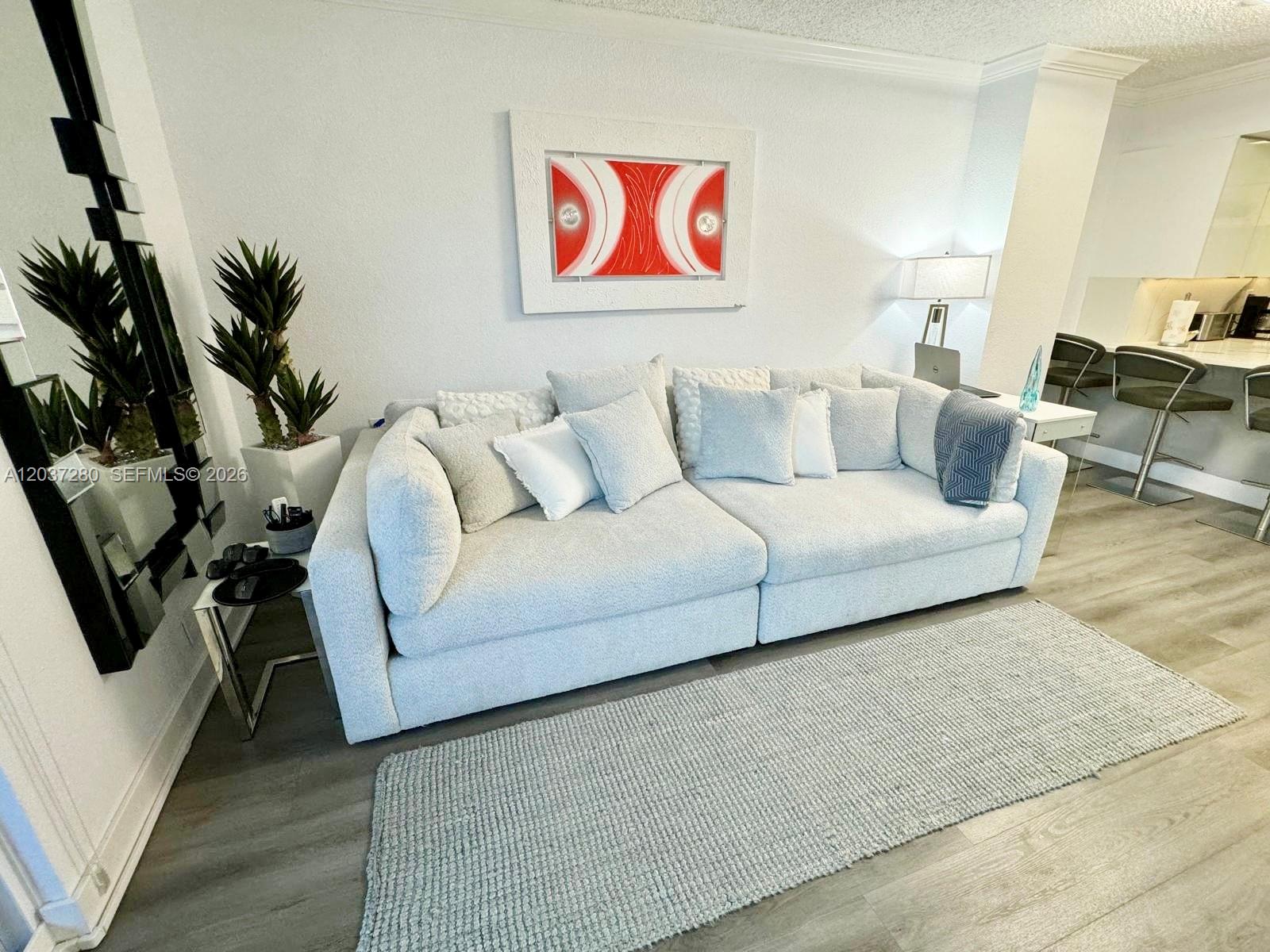 A living room features a light gray sofa, a textured rug, and modern wall art — 2501 S Ocean Dr # L14, Hollywood FL 33019, HOLLYWOOD, FL