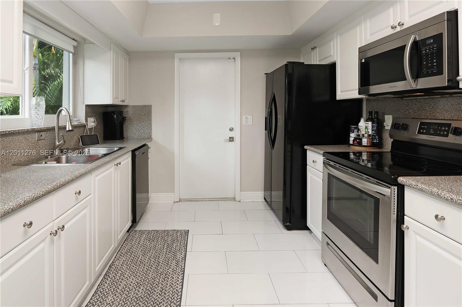 A kitchen features white cabinets, granite countertops, stainless steel appliances, and a black refrigerator — 1333 Tyler St, Hollywood FL 33019, HOLLYWOOD, FL