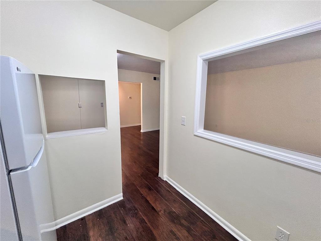 A kitchen area features wood-look flooring, a white refrigerator, and two wall cutouts — 4455 38TH TERRACE N UNIT B12, ST PETERSBURG, FL