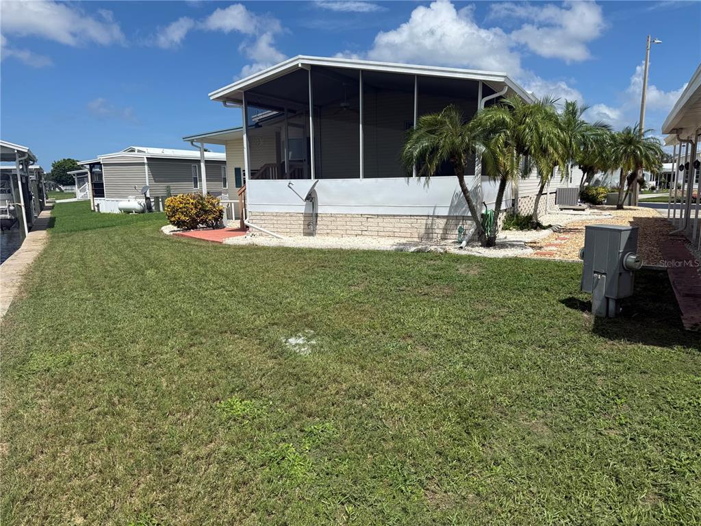 A mobile home with a screened-in porch and palm trees sits on a grassy lot — 138 S SAINT THOMAS CIRCLE, APOLLO BEACH, FL