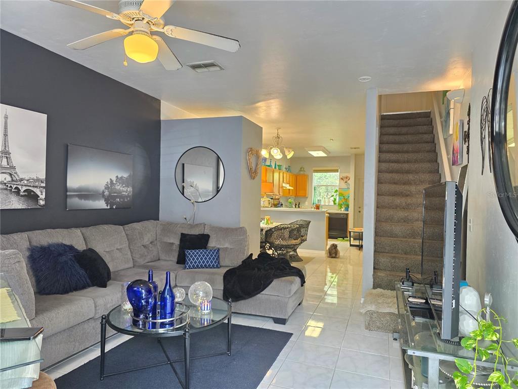 A living room with a gray sectional sofa, tiled floors, and stairs leading to an upper level — 4415 SW 34TH ST UNIT 410, GAINESVILLE, FL