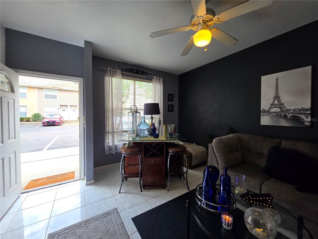 A living room with a dining table, sofa, and an open door leading outside — 4415 SW 34TH ST UNIT 410, GAINESVILLE, FL
