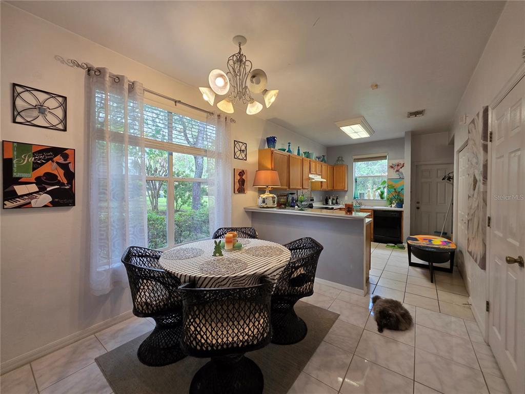 A dining area with a round table and wicker chairs sits adjacent to a kitchen — 4415 SW 34TH ST UNIT 410, GAINESVILLE, FL