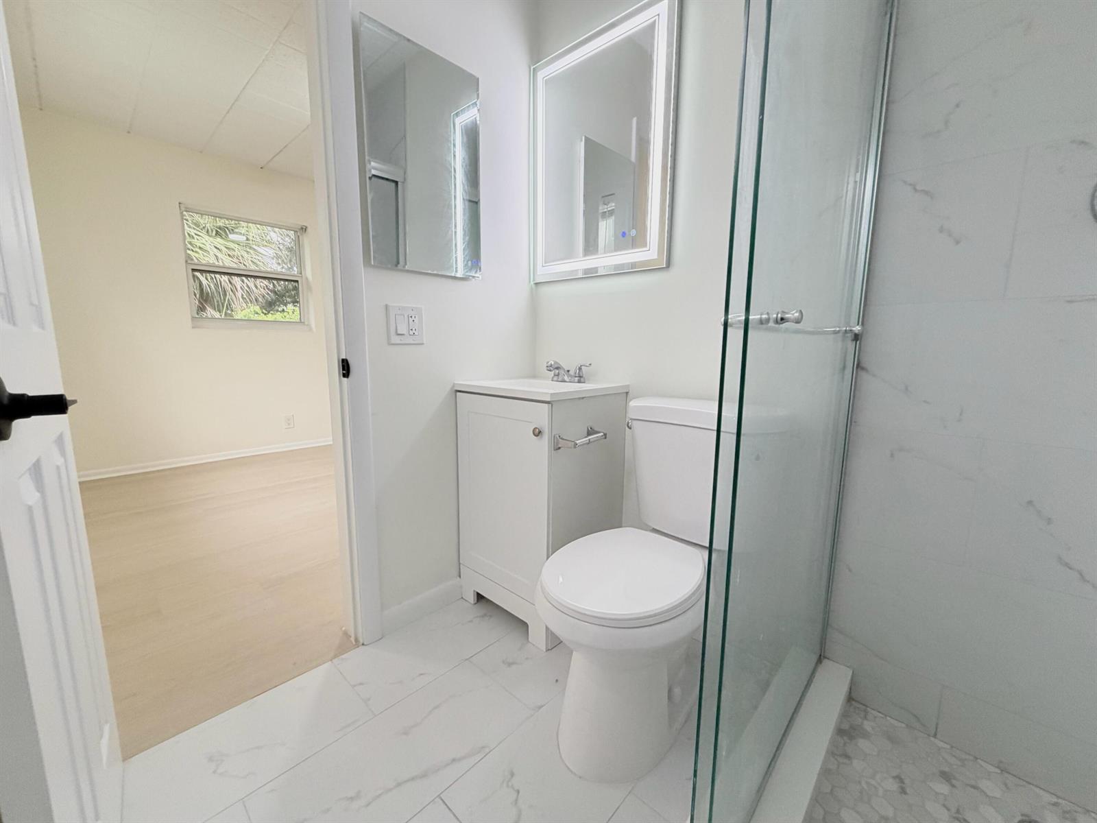 A small bathroom features a white vanity, a toilet, and a glass-enclosed shower — 1713 Florida Avenue Unit B4, West Palm Beach FL 33401, WEST PALM BEACH, FL