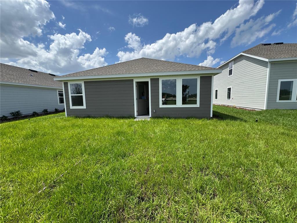 The exterior rear view of a single-story house features gray siding, a door, and windows — 5596 MORANT BAY PATH, KISSIMMEE, FL