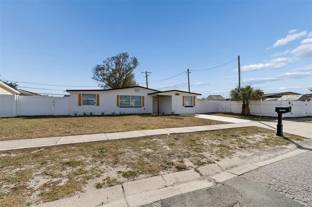 A single-story white house with a fenced yard and a concrete driveway — 7910 W POWHATAN AVENUE, TAMPA, FL